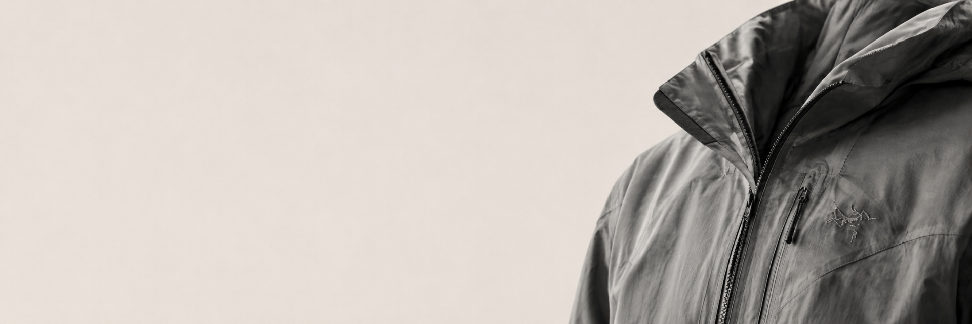 Editorial-Bild einer grauen technischen Archive-Jacke mit Kapuze, minimalistischer Studio-Look